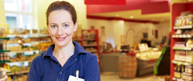 LÃ¤chelnde Ã¤ltere Marktleiterin im Supermarkt mit verschrÃ¤nkten Armen